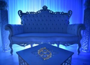 Luxueux canapé baroque blanc pour événement, baigné de lumière bleue. Table basse avec logo doré "Events For You".