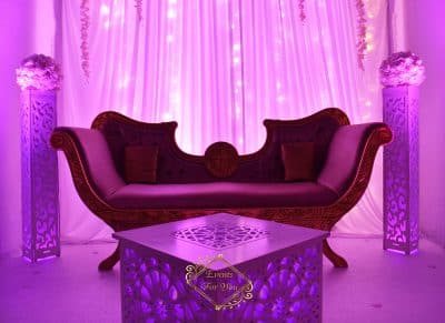 Salon événementiel magenta : sofa royal en velours, table lumineuse. Piliers décoratifs arabesques. Organisation Events For You