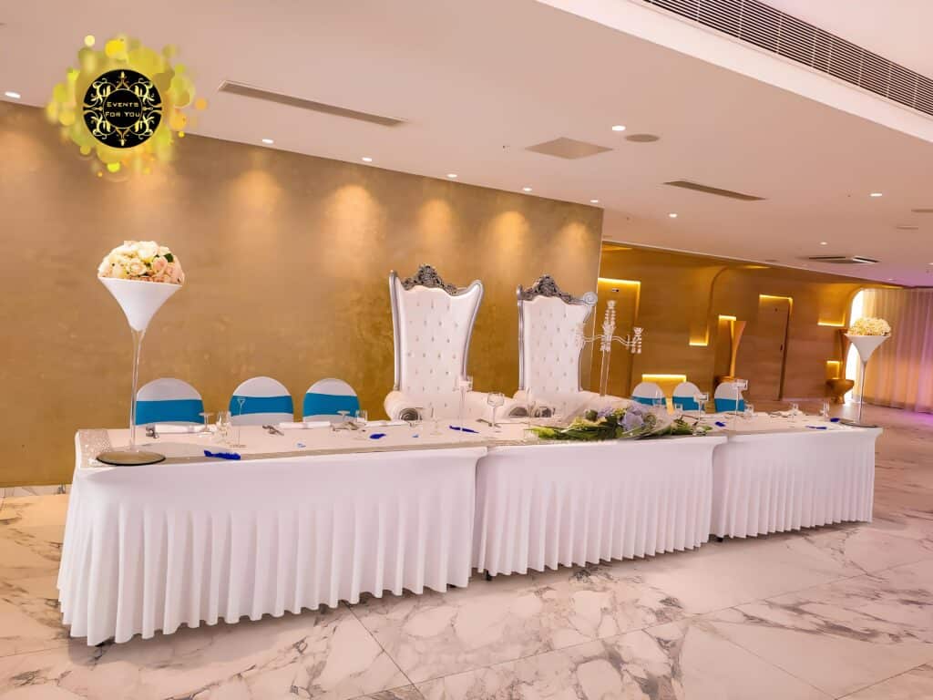 Table d'honneur de mariage luxe – Décoration élégante Décoration événementielle luxe: longue table d'honneur, chaises de trône blanches, accents bleu. Logo "EVENTS FOR YOU".